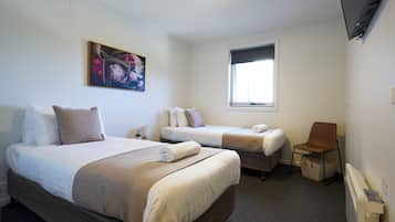 Habitación de hotel con dos camas, una ventana, un cuadro y un televisor.
