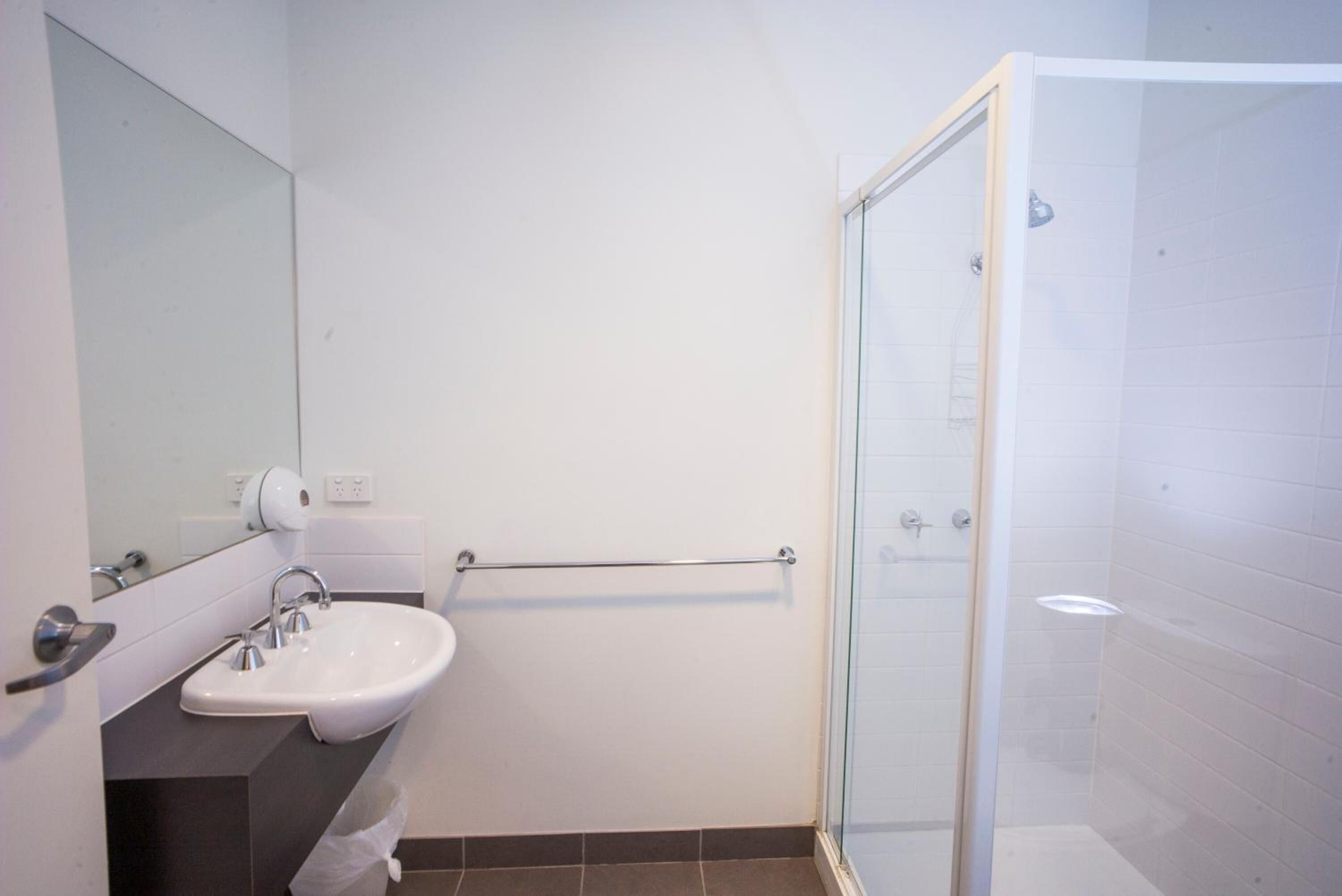 Un baño con lavabo, espejo y cabina de ducha de vidrio.