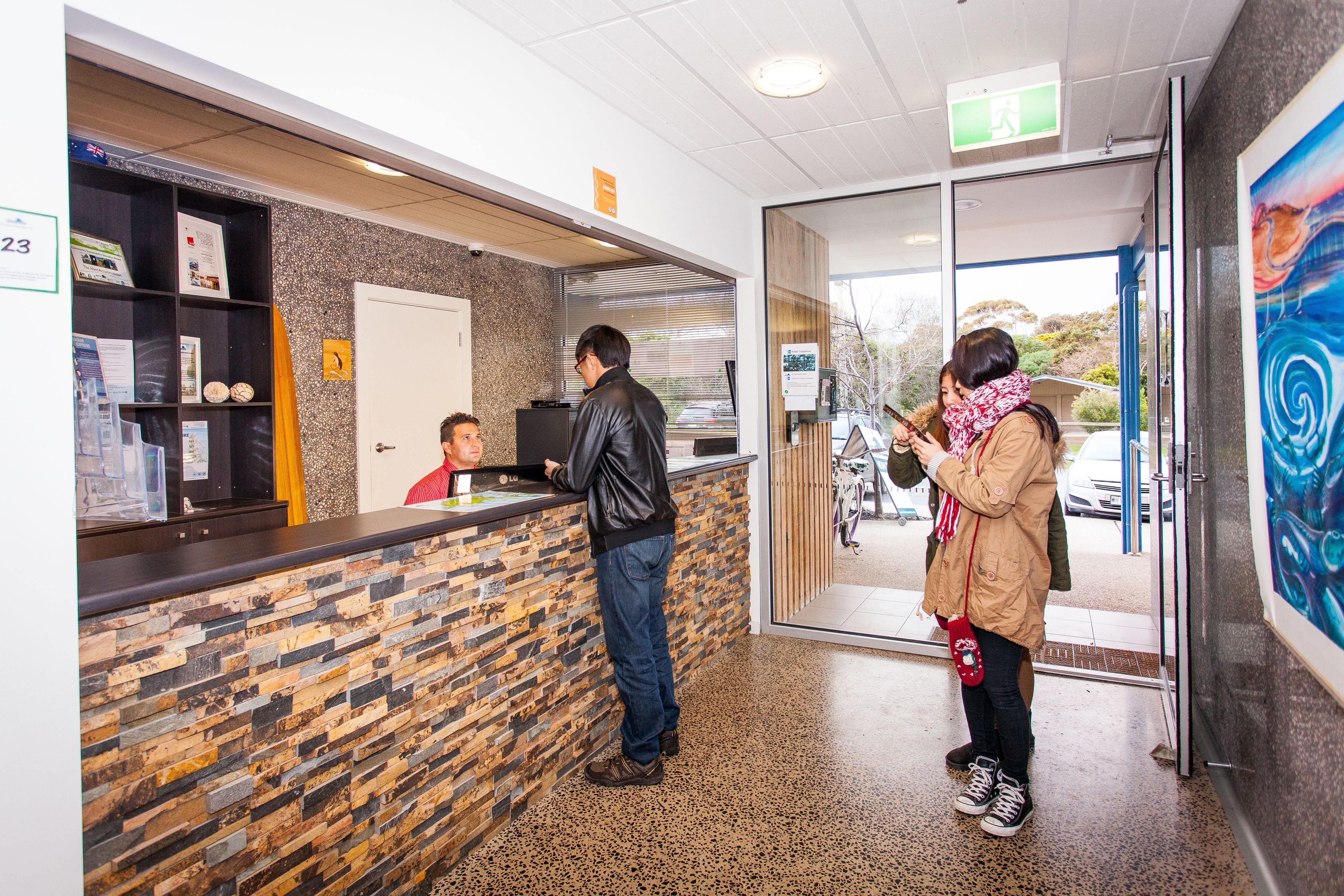 A reception area with a stone wall, a counter, and a glass door leading outside.