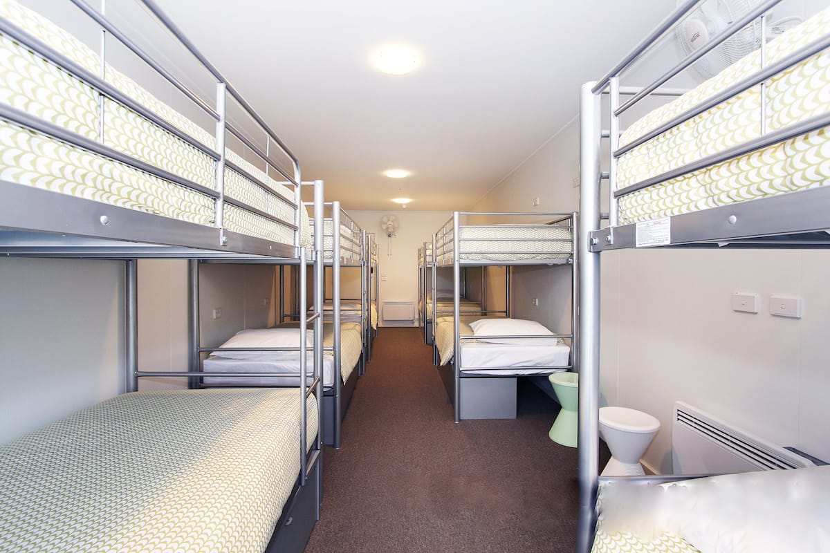 A dormitory room with bunk beds, a toilet, and a radiator.