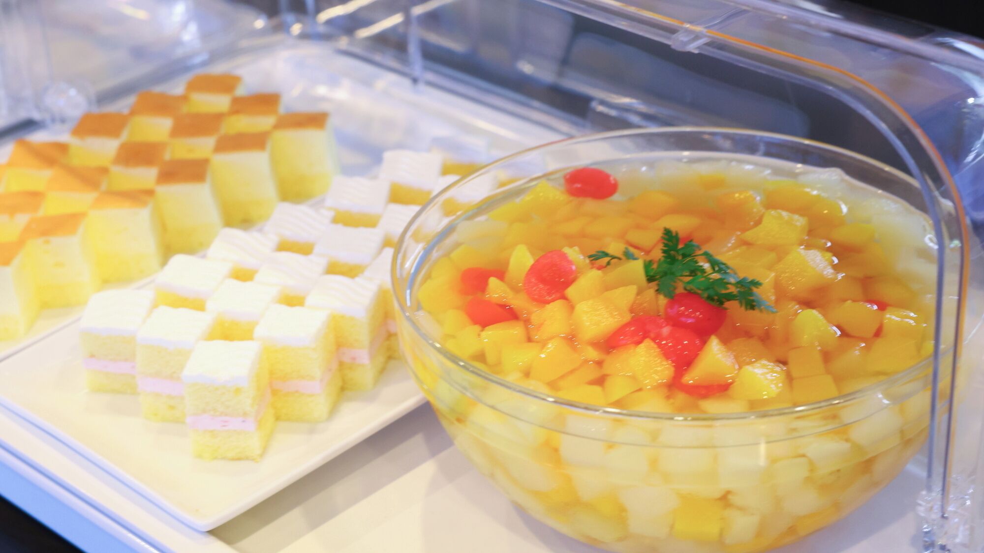 A buffet with a variety of desserts including a fruit salad and a layered cake.