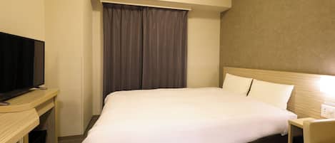 A hotel room with a bed, a television on a desk, and a curtain.
