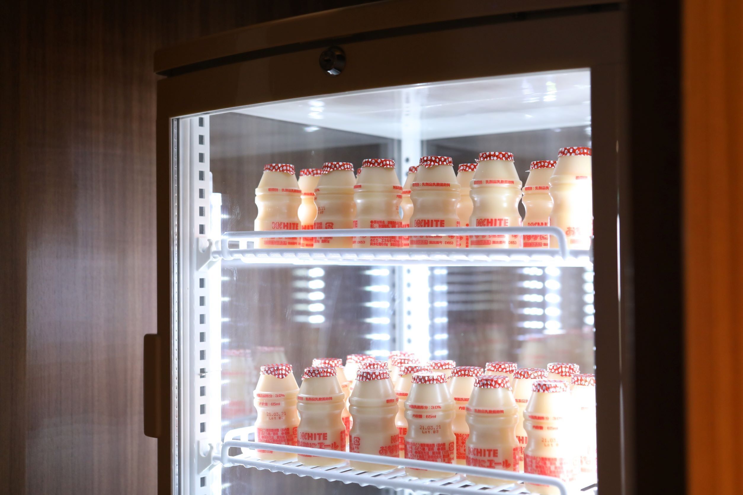 Vitrina refrigerada con varias estanterías llenas de botellas.
