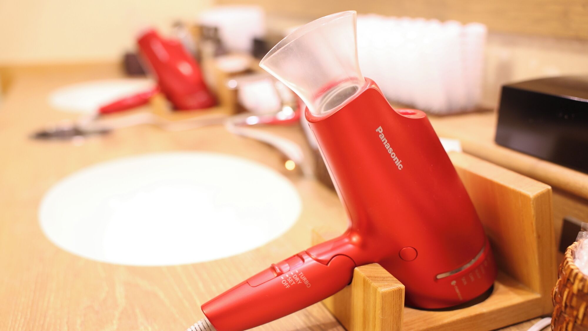 Un sèche-cheveux rouge de la marque Panasonic, posé sur un support en bois.