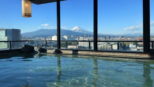 A hot spring pool with a view of a cityscape and a mountain.