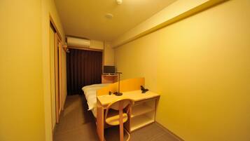 A compact hotel room with a single bed, a desk, and a chair.
