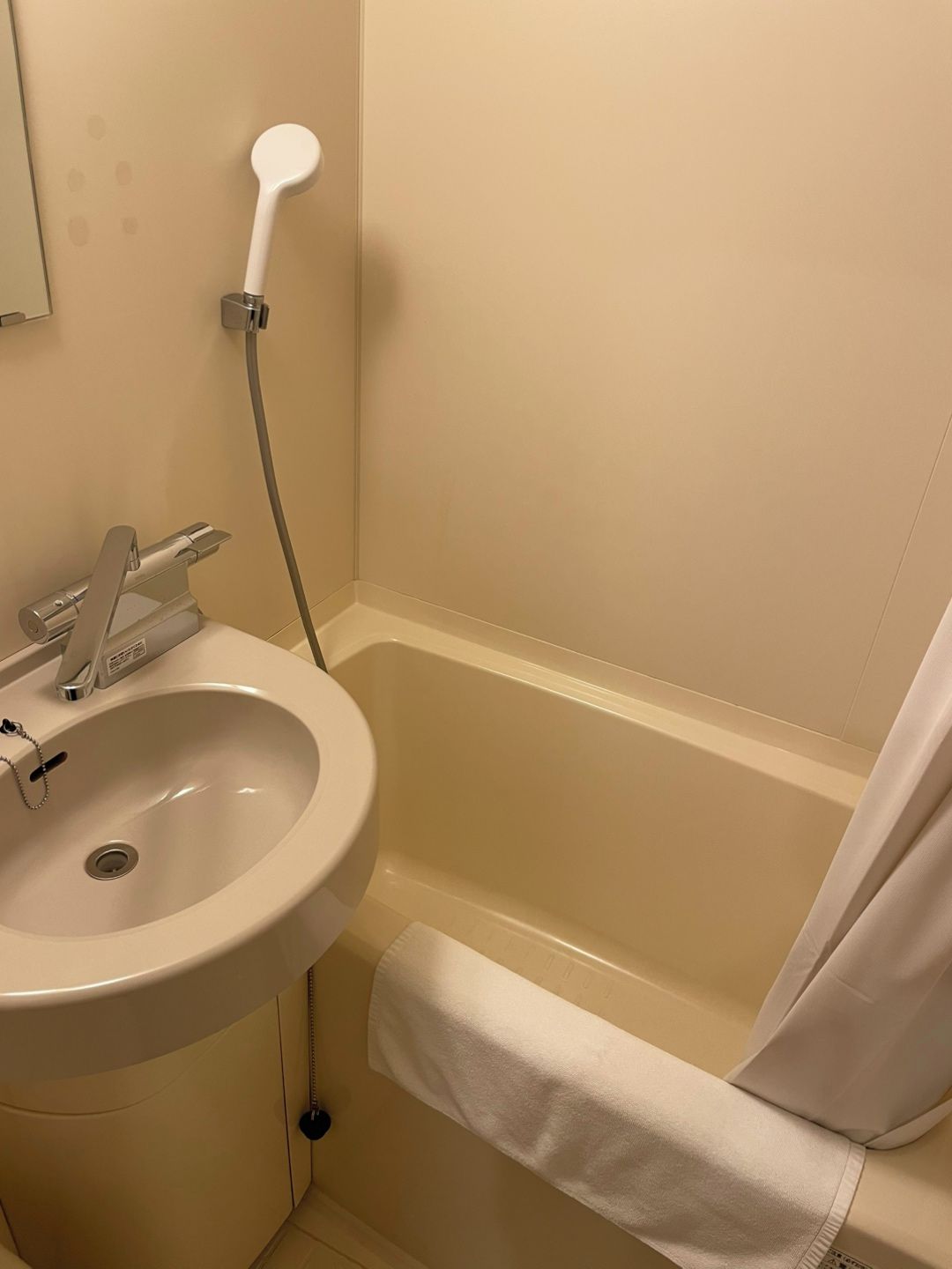 A bathroom with a sink, a shower, and a towel rack.