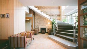 A spacious lobby with a curved staircase, a fireplace, and a seating area with striped sofas.