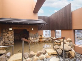 An outdoor area with a stone wall, a small water feature, and a wooden structure.