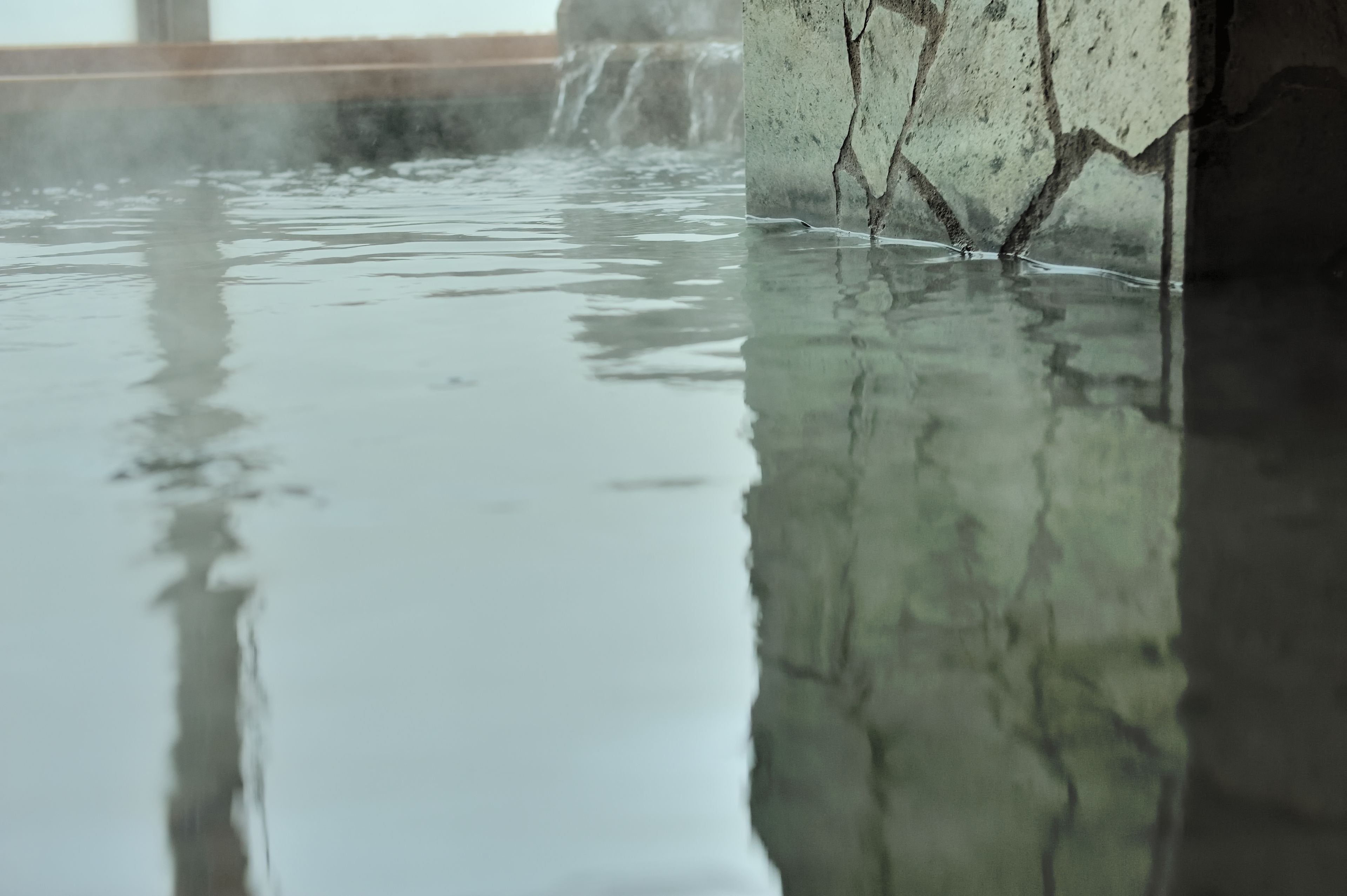 A reflective water surface with a concrete structure in the background.