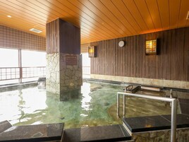 Un baño de aguas termales con escalones de piedra y paneles de madera.