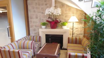 A cozy living room with striped sofas, a fireplace, and potted plants.