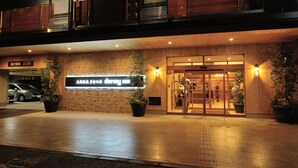 A hotel entrance with a wooden facade, a sign indicating a 2.0M parking space, and potted plants.
