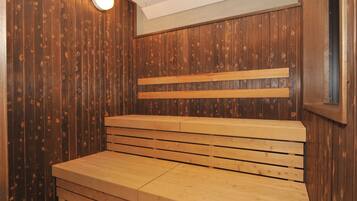 Un sauna avec des bancs en bois et un éclairage au plafond.