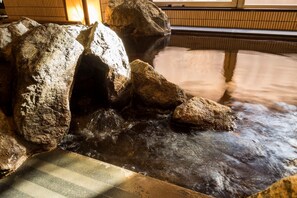 A hot spring area with large rocks and a wooden platform. - Dormy Inn Obihiro Natural Hot Spring (Obihiro)