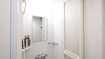 A bathroom with a shower, a mirror, and toiletries on a shelf.