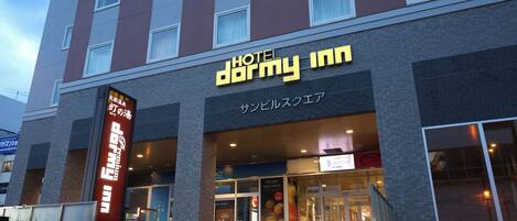A hotel with a sign reading 'HOTEL DORMY INN' and a visible entrance.
