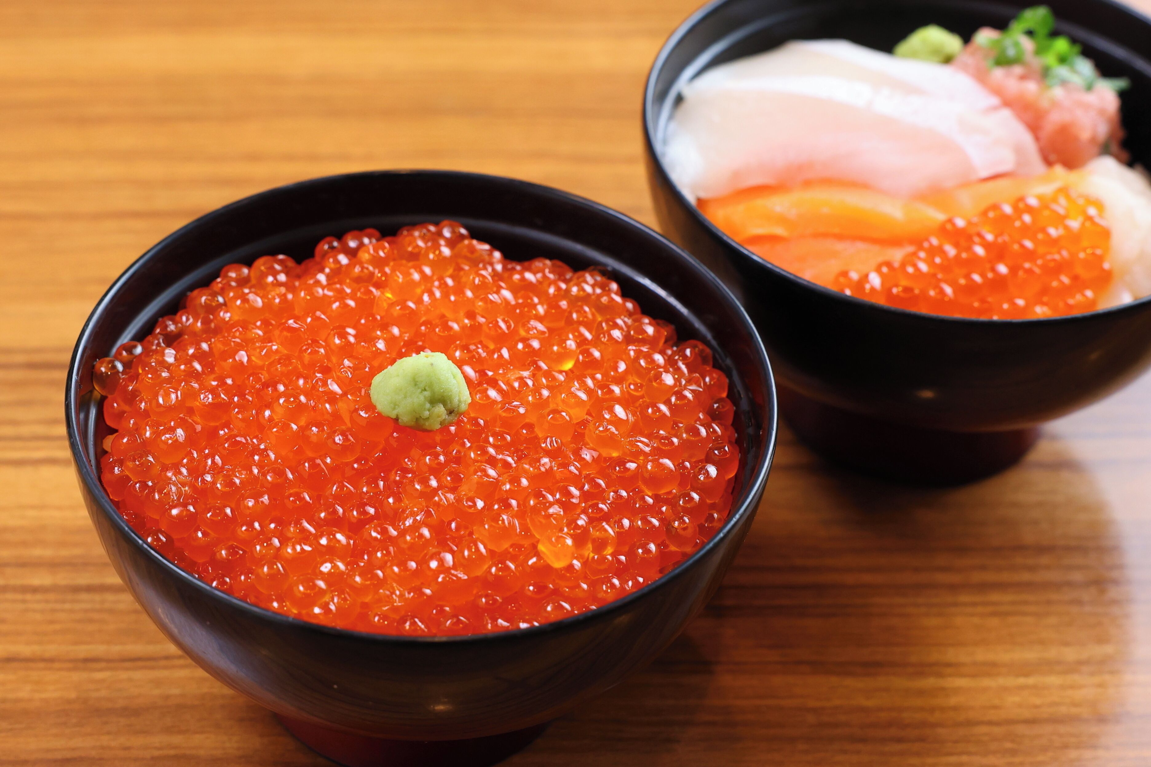 Two bowls of red caviar on a wooden table.