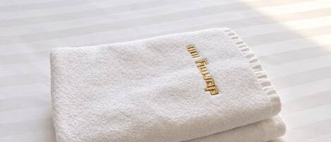 A folded white towel with embroidered text on a striped surface.