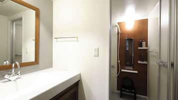 A bathroom with a sink, mirror, towel rack, shower, and a small stool.