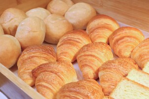 Una bandeja de madera con diferentes tipos de panes y cruasanes.