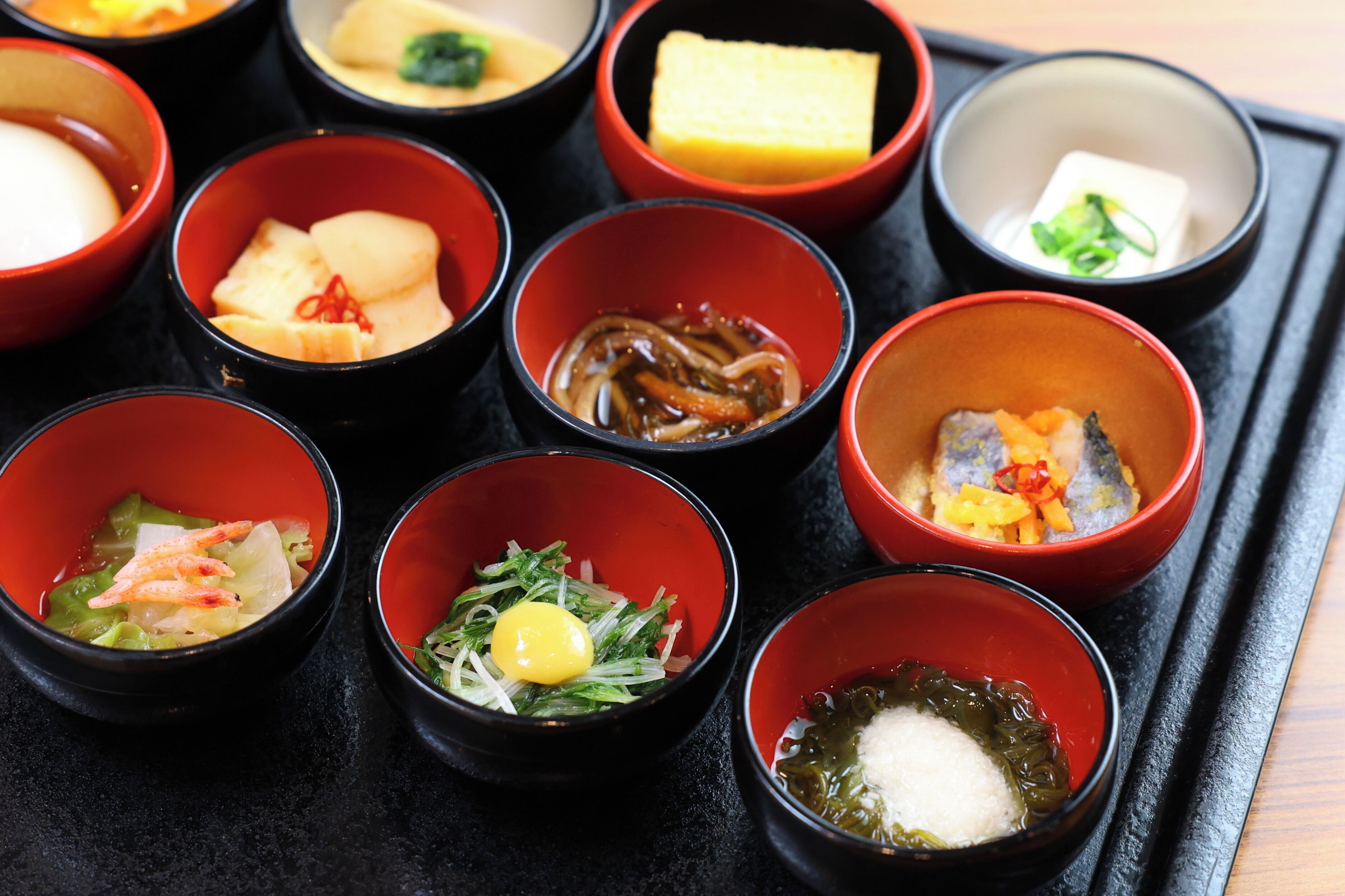 Eine Schale mit verschiedenen japanischen Gerichten, darunter Sushi, Sashimi und andere Köstlichkeiten.