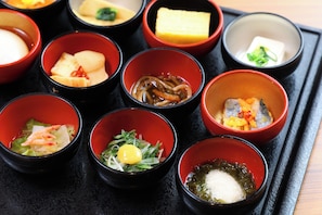 A tray of various Japanese dishes in small bowls, including sushi, sashimi, and other delicacies.