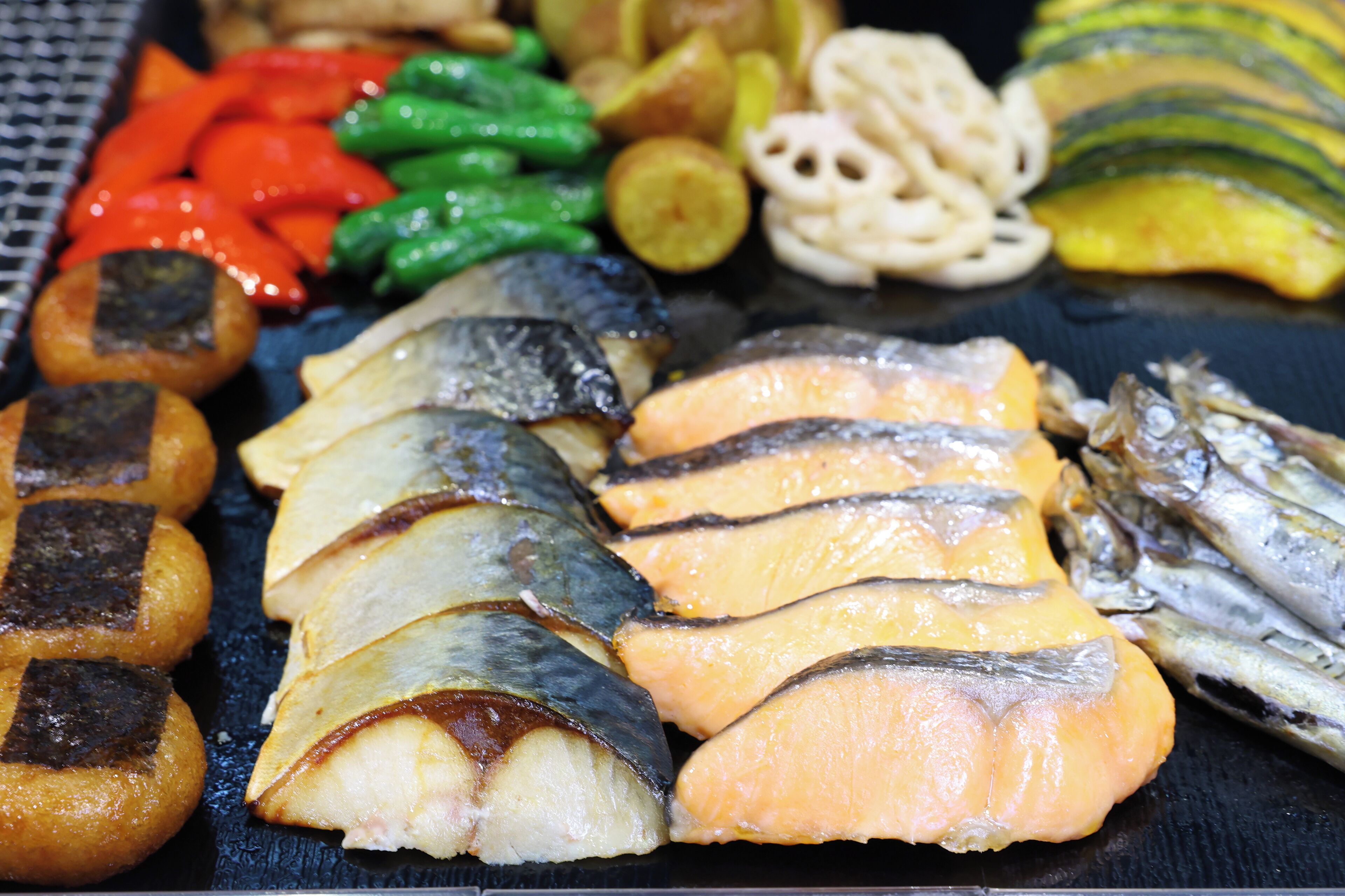 A variety of grilled foods including fish, vegetables, and possibly some dumplings.