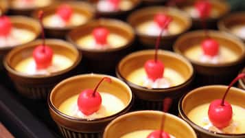 A series of small, round, brown dishes with a creamy substance and a red topping, arranged on a tray.