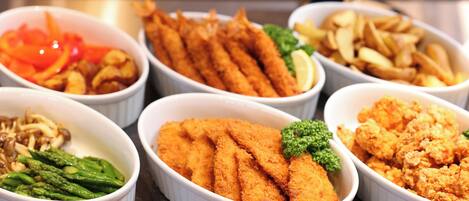 A variety of dishes including breaded fish, asparagus, and fries in white bowls.