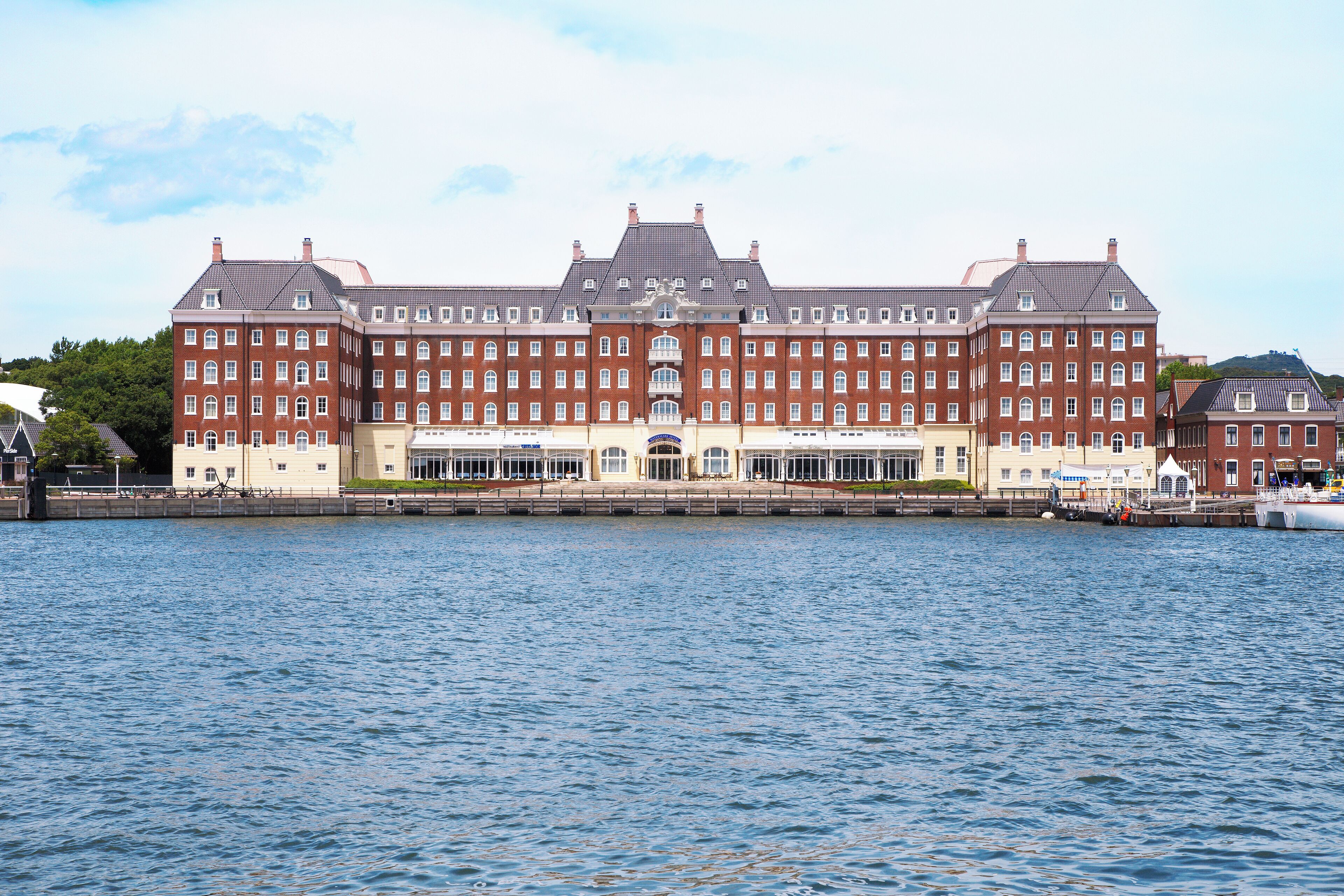 A large, historic building with multiple floors, a central entrance, and a waterfront view.