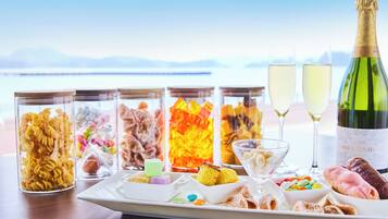 A table with various food items and two glasses of champagne, set against a scenic backdrop.