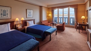 A hotel room with two beds, a desk, a chair, and a view of the outdoors. - Hotel Den Haag Huis Ten Bosch (Sasebo)