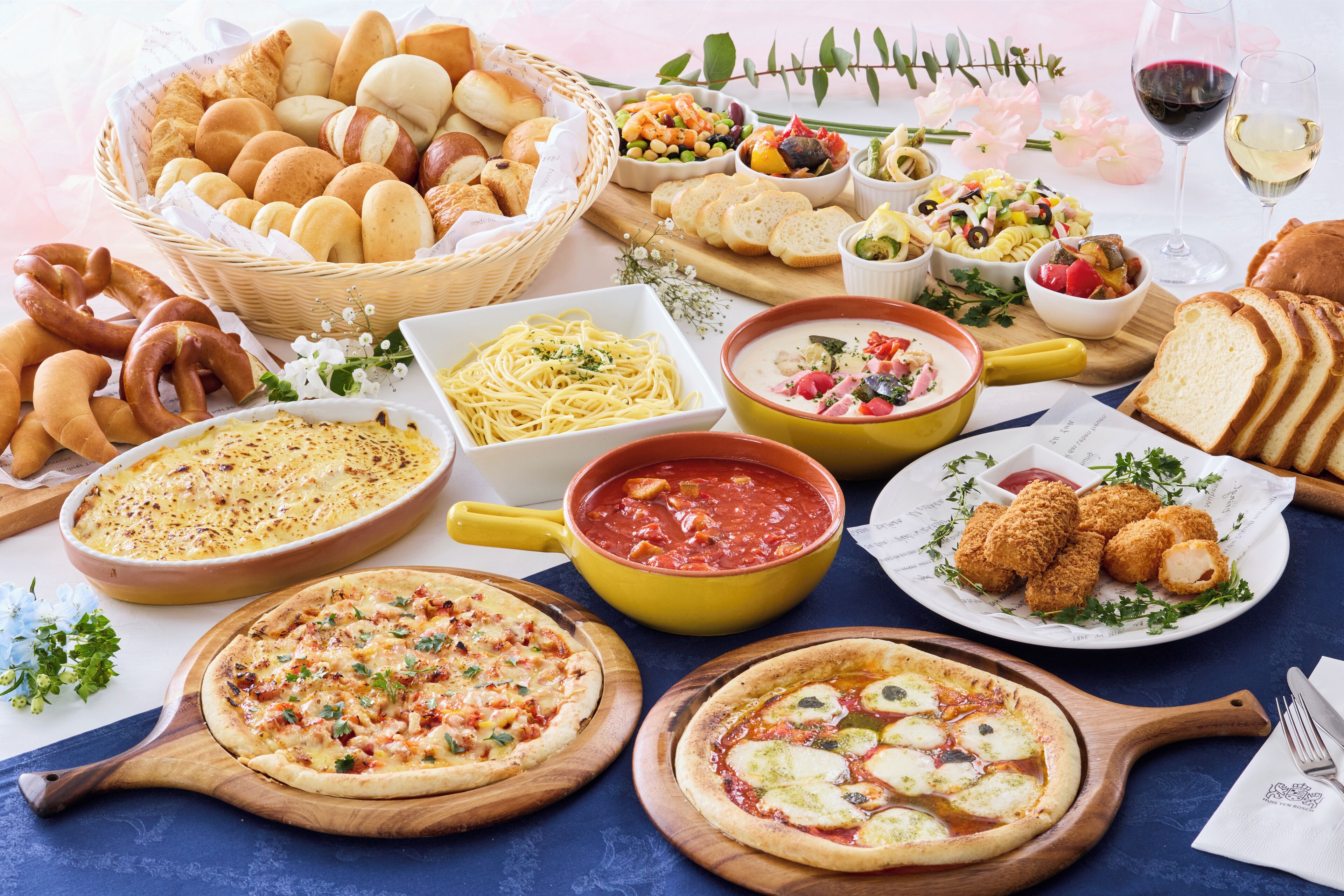 A variety of Italian dishes including pizzas, pasta, and bread, arranged on a table.