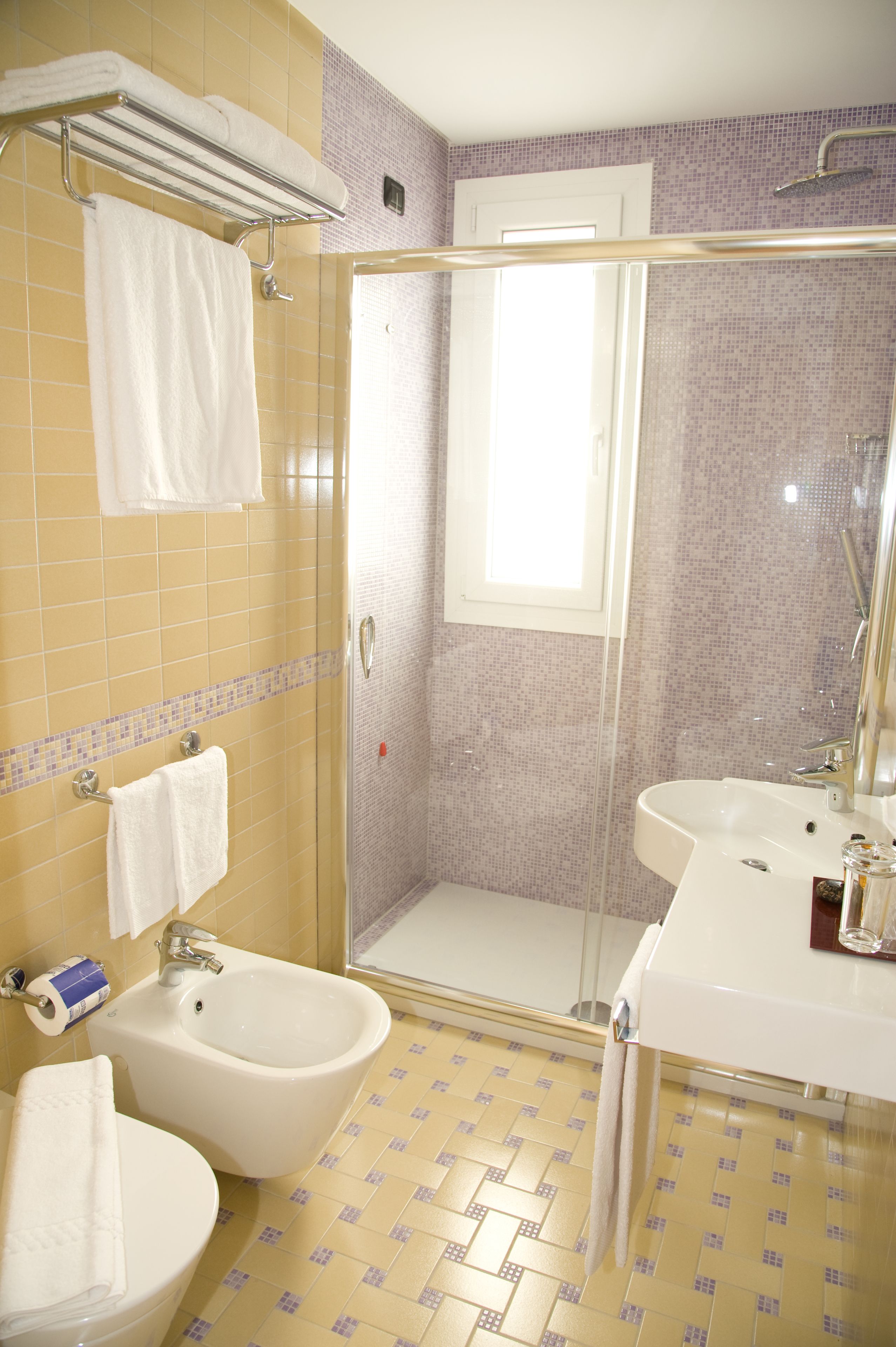A bathroom with a shower, bidet, and sink.