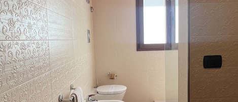 A bathroom with a marble sink, two toilets, a bidet, and a window with a view.
