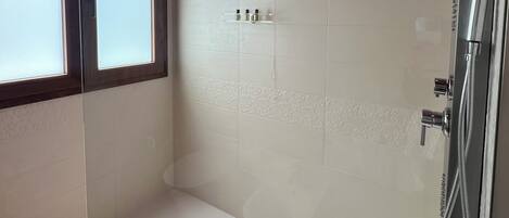 A modern bathroom with a shower, a window, and a ceiling light.