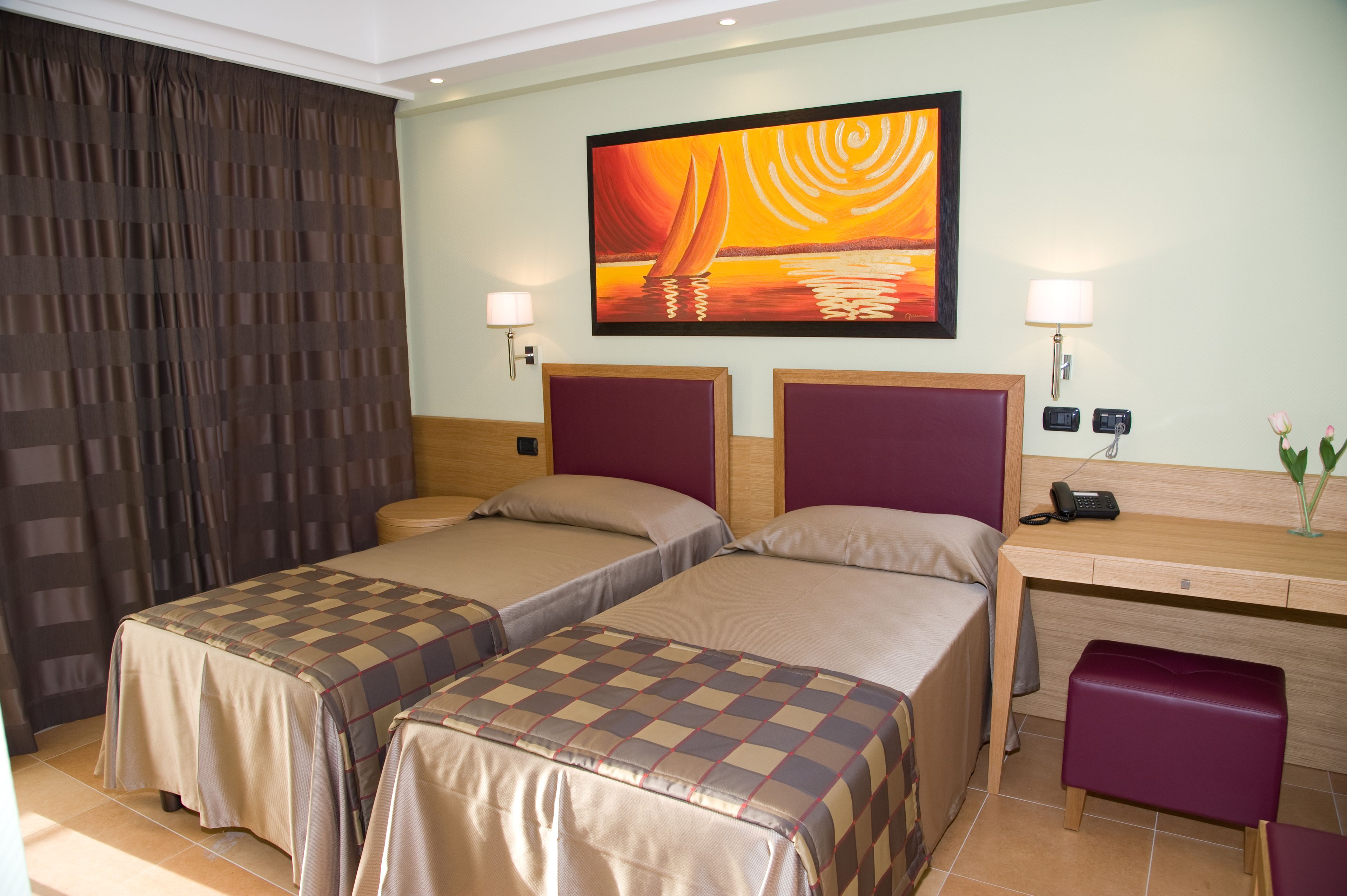 A hotel room with two beds, a desk, a chair, a phone, and a painting on the wall.