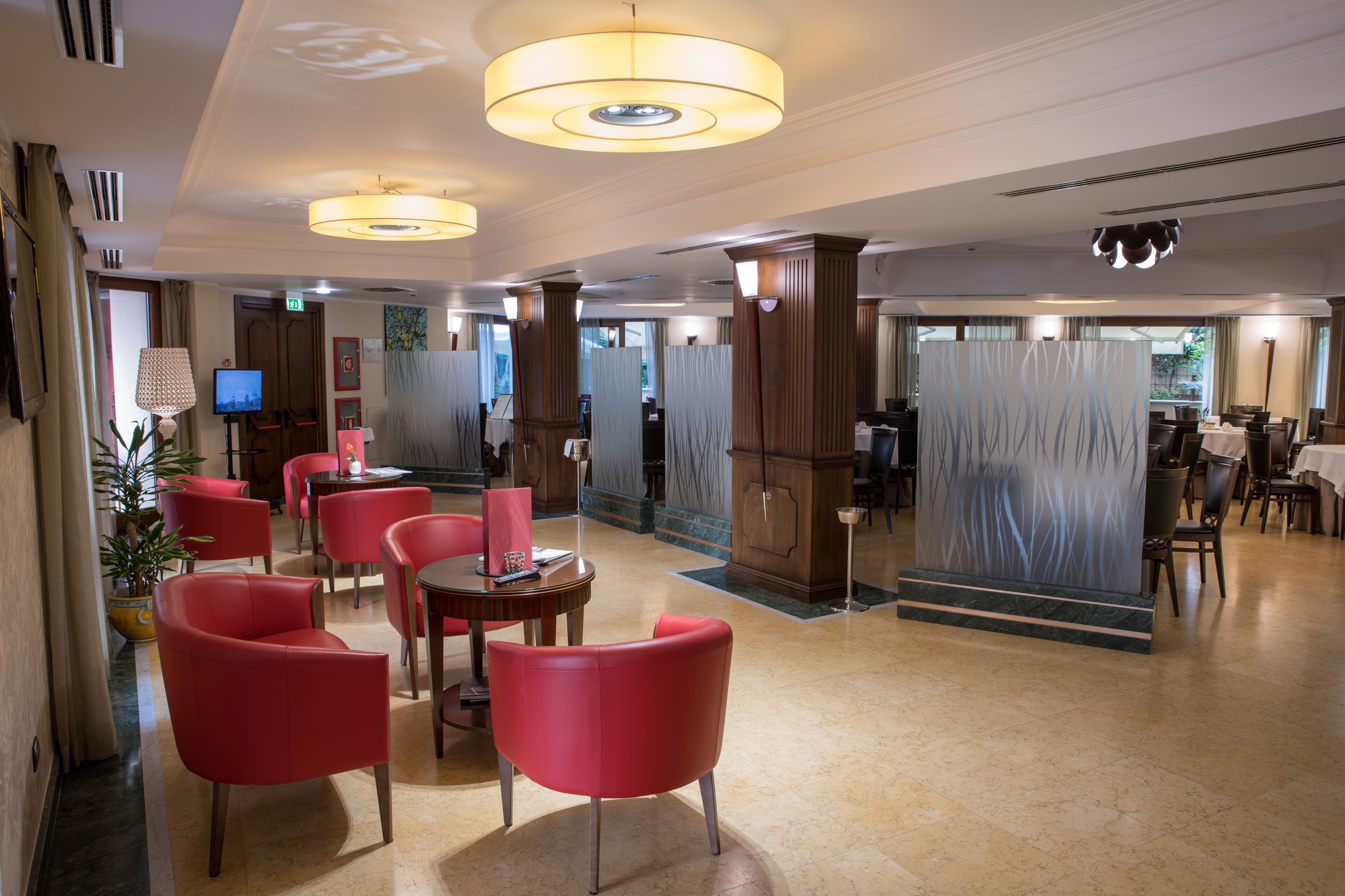 A hotel lobby with red chairs, a TV, and a large decorative pillar.