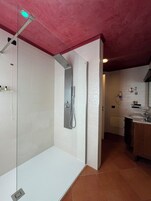 Un baño moderno con ducha de vidrio, un lavabo blanco y un espejo.