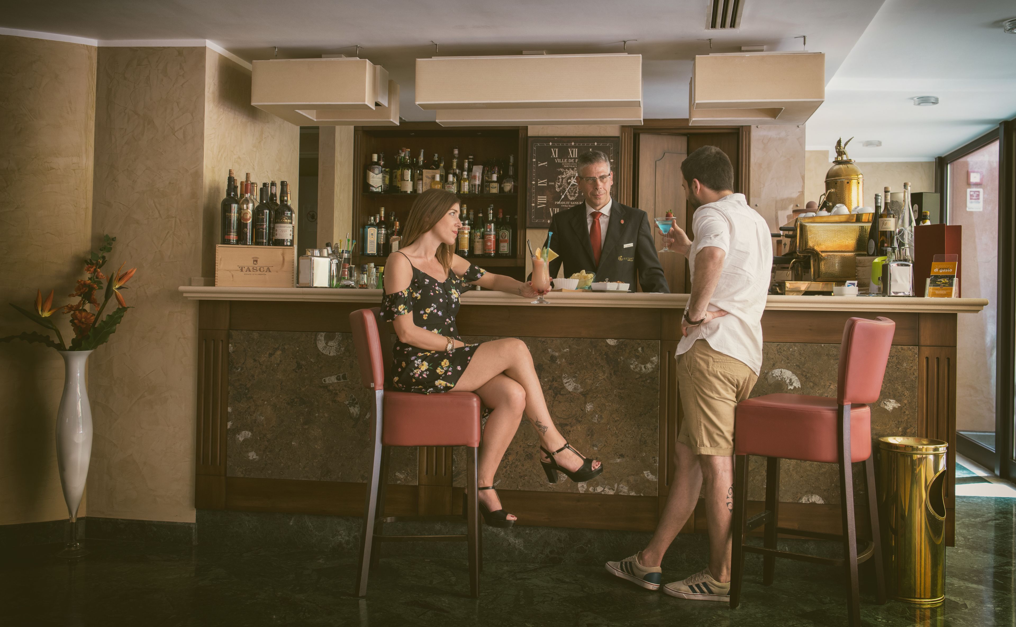 A bar area with a counter, bar stools, and a variety of bottles.