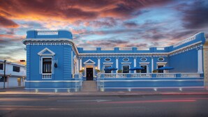 A blue building with a grand entrance, white railings, and potted plants. - Hotel Casa Azul (Mérida)
