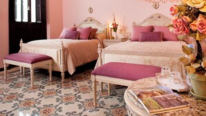 A bedroom with two beds, a chandelier, a decorative mirror, and a floral arrangement. - Hotel Casa Azul (Mérida)