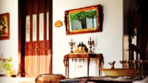 A room with a wooden door, a small table with a clock, and a framed picture on the wall. - Hotel Casa Azul (Mérida)