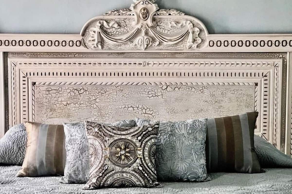 A bed with a decorative headboard, multiple pillows, and a textured bedspread.