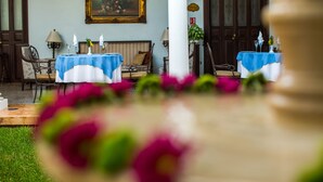 A dining area with tables set for a meal, a painting on the wall, and a large column in the foreground. - Hotel Casa Azul (Mérida)