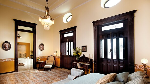 A traditional room with a large bed, a desk, and a chair. There is a mirror on the wall and a chandelier. - Hotel Casa Azul (Mérida)