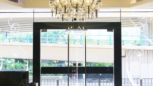 A lobby with a chandelier, a black sofa, and a glass entrance. - Vela Boutique Hotel (Hong Kong)