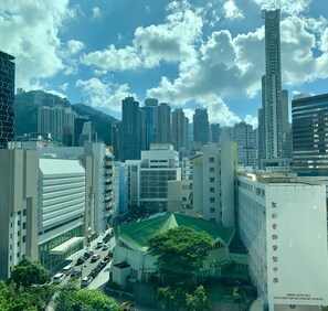 A cityscape with modern buildings, a prominent white building with a green roof, and a tall skyscraper. - Vela Boutique Hotel (Hong Kong)