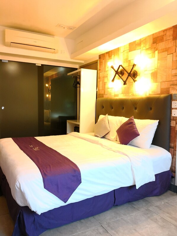 A modern hotel room with a large bed, a wooden headboard, and a wall-mounted light fixture. - Vela Boutique Hotel (Hong Kong)